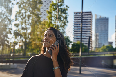 Young businesswoman with phone laughing on street