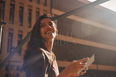 Young businesswoman with tablet against building