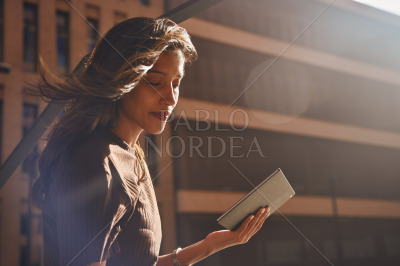 Young confident businesswoman with tablet in sun