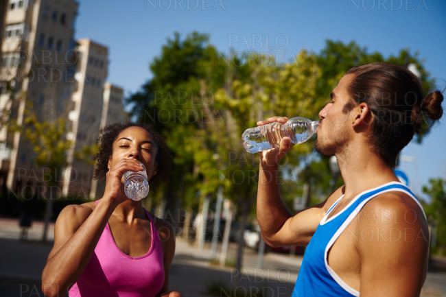 Active couple drinking water outdoors in the city