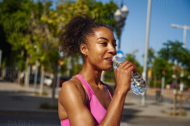 Athletic young woman drinking water outdoors