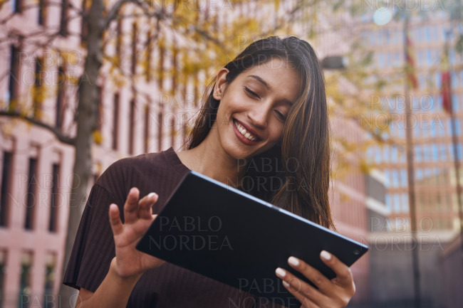 Cheerful businesswoman with tablet on street