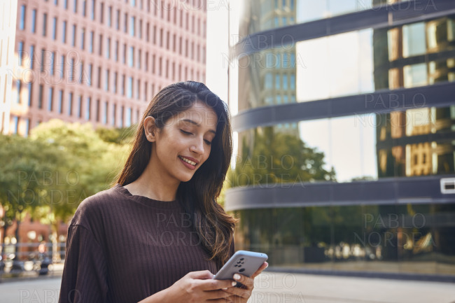 Cheerful young businesswoman holding mobile phone