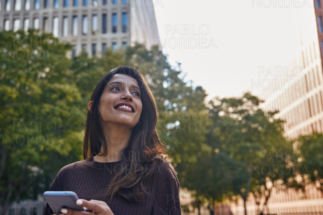 Smiling businesswoman with mobile phone on street