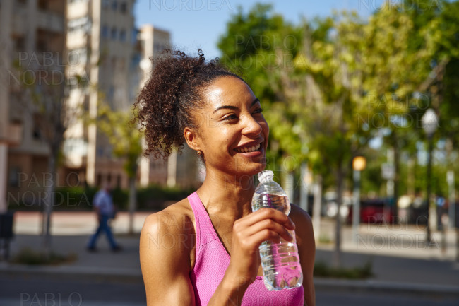 Smiling young woman holding a bottle of water