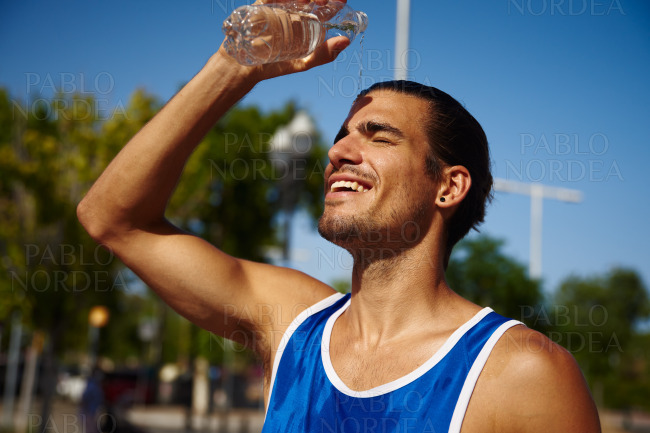 Sportsman smiling and pouring water on his face