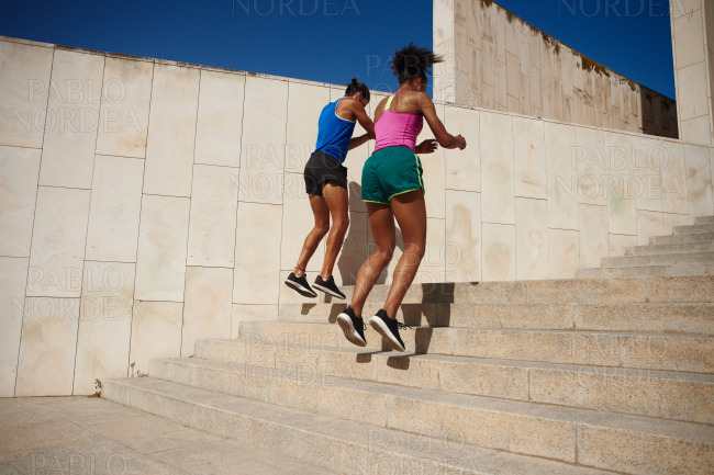 Sporty young couple doing stair jumps outdoors