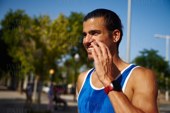 Sporty young man smiling with water on his face