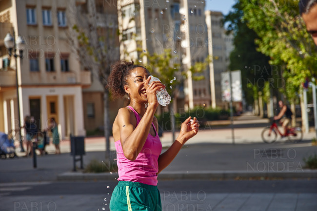 Sporty young woman playing with water outdoors