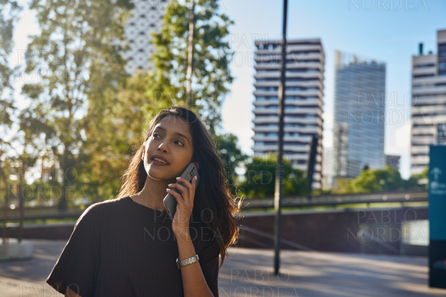 Stylish businesswoman standing with phone in city
