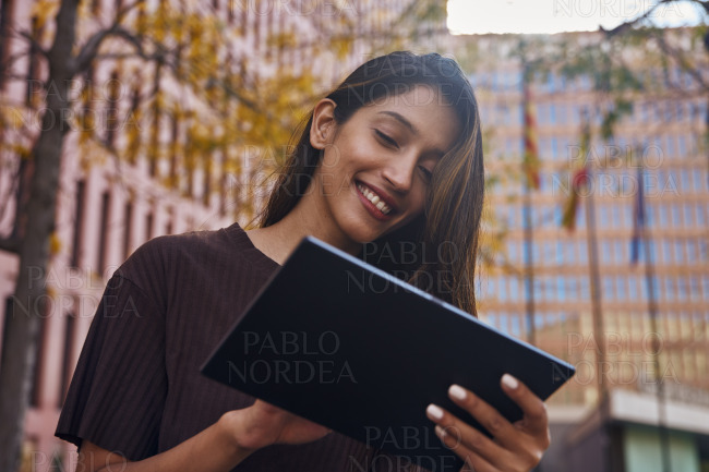 Young and busy businesswoman with tablet on street