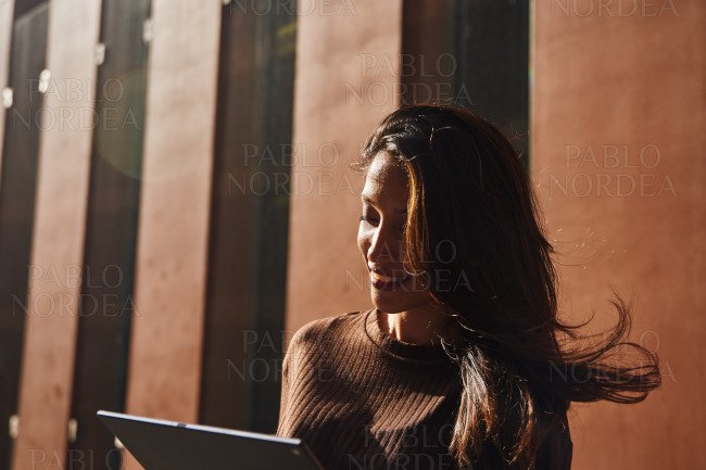 Young beautiful businesswoman with tablet on stree