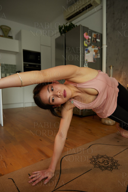 Young beautiful sporty woman bending in apartment