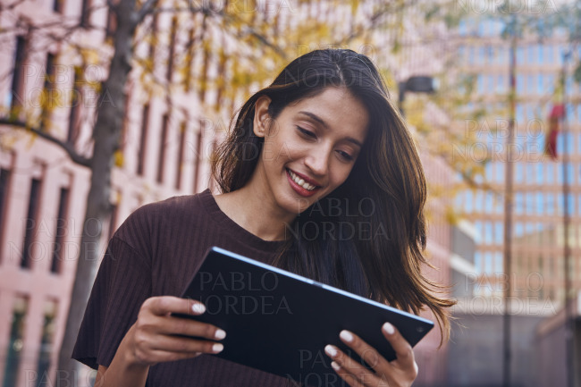 Young businesswoman examining tablet on street