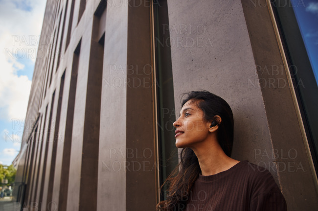 Young businesswoman leaning against building wall