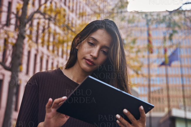 Young businesswoman looking at tablet on street