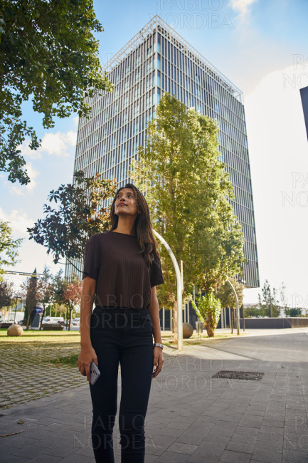 Young businesswoman standing on street with phone
