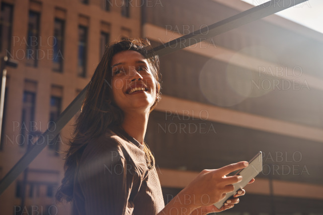 Young businesswoman with tablet against building