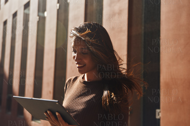 Young businesswoman working on tablet on street