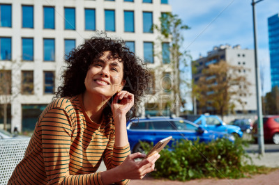 Smiling young woman with cellphone looking away