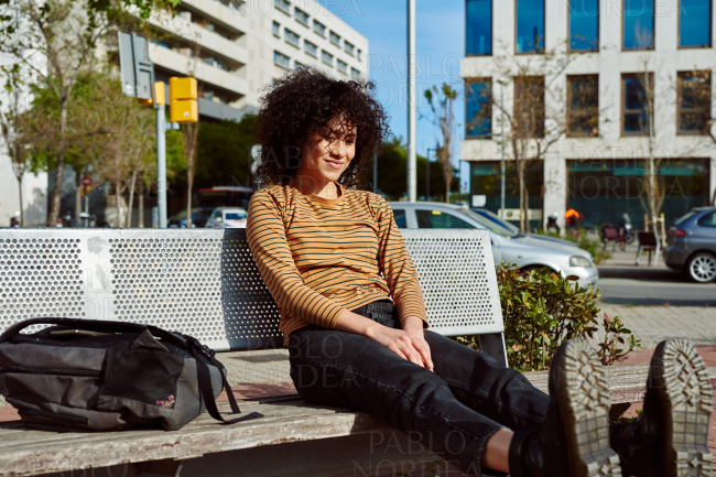 Cute young woman relaxing on a bench in the city