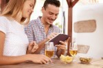 Smiling couple with beers and touchpad