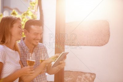 Giggling couple with touchpad and beers