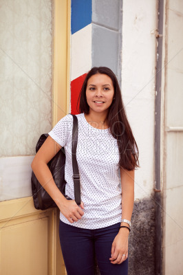 Girl leaning against a multicoloured pillar