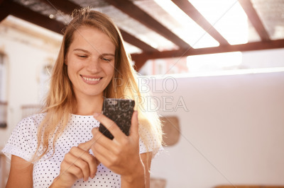 Happily smiling blond girl using a cellphone