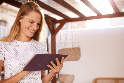 Happy blond girl smiling at touchpad