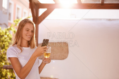 Smiling blond woman with cellphone and beer
