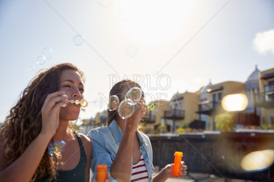 Two happy young girls blowing bubbles