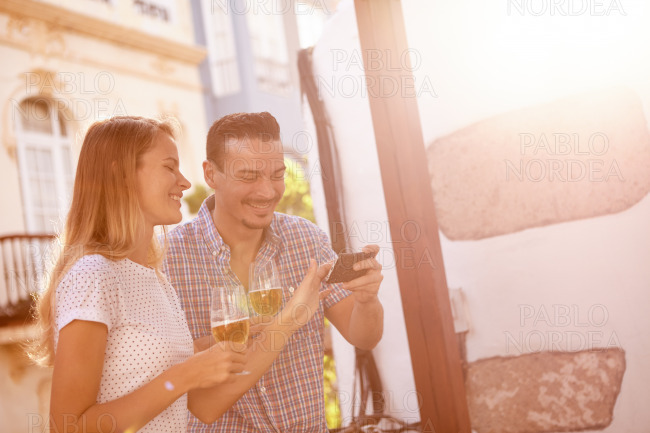 Beautiful couple with beers and cellphone