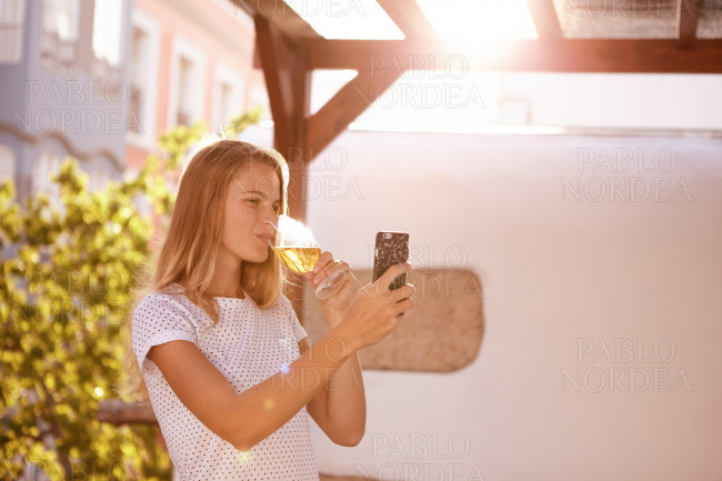Blond girl with cellpone drinking beer