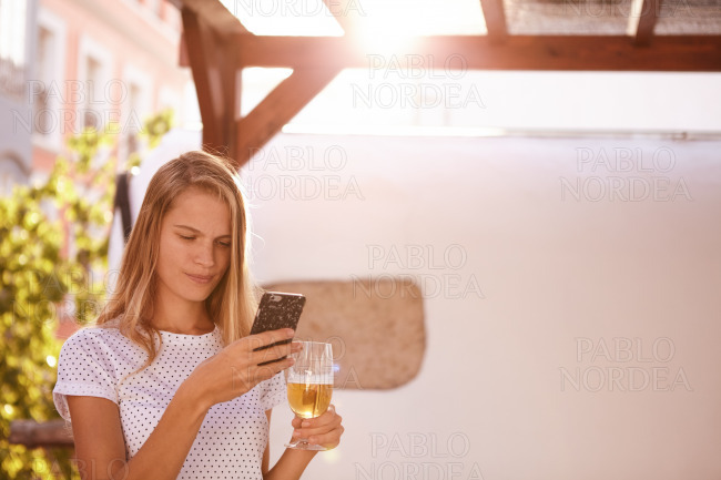 Concentrating blond with cellphone and beer