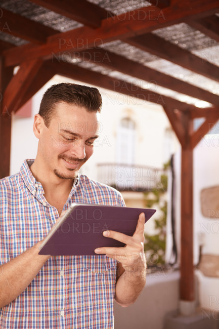 Cool dark haired guy smiling at tablet