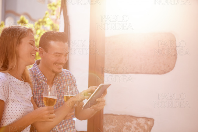 Giggling couple with touchpad and beers