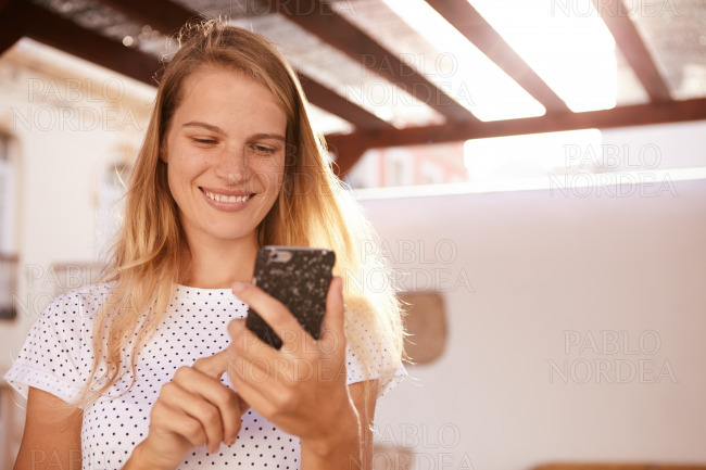 Happily smiling blond girl using a cellphone