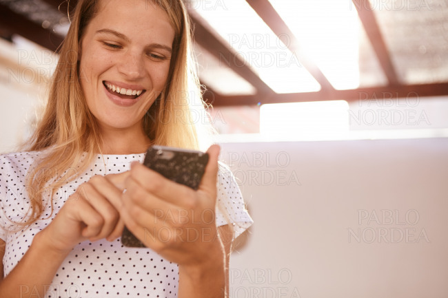 Happily smiling blond girl with cellphone