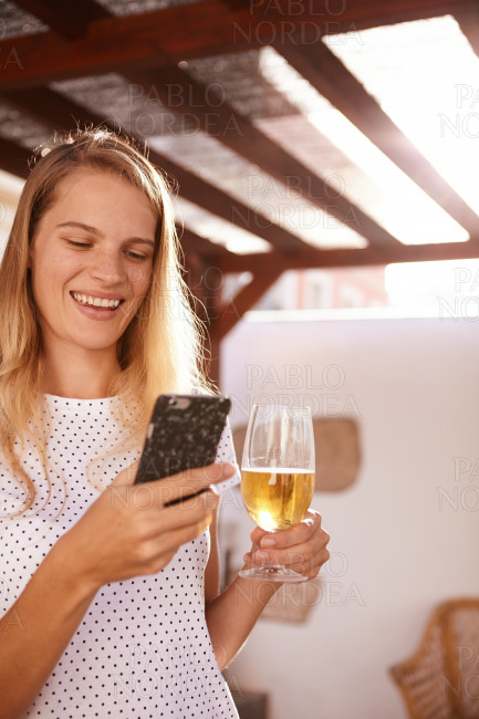 Happy blond with her cell and beer