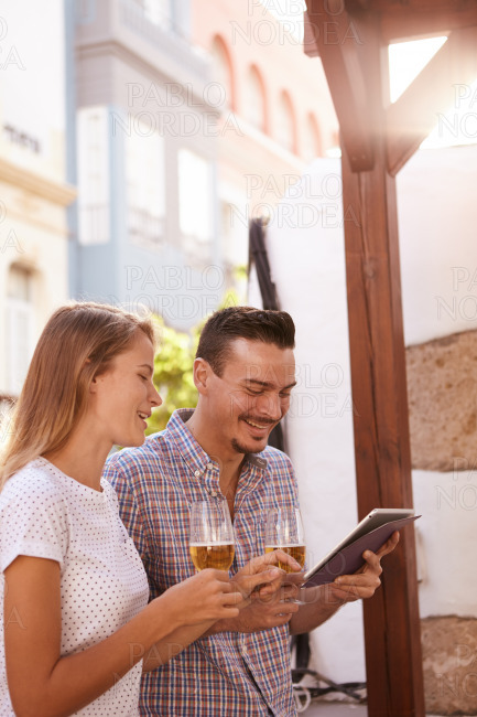 Happy couple with beers using tablet