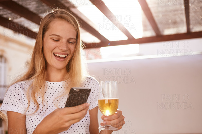 Laughing blond with beer and cellphone