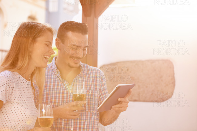 Laughing couple with beers and touchpad