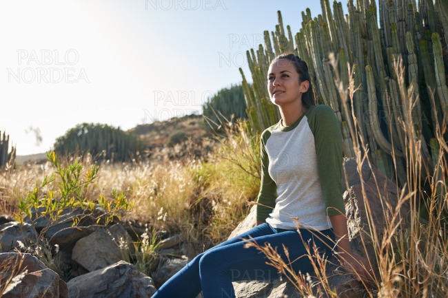 Lovely young lady sitting on rock