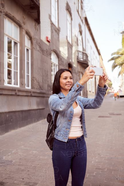 Pretty young girl in narrow street with cell phone
