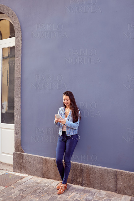 Pretty young girl leaning against a blue wall