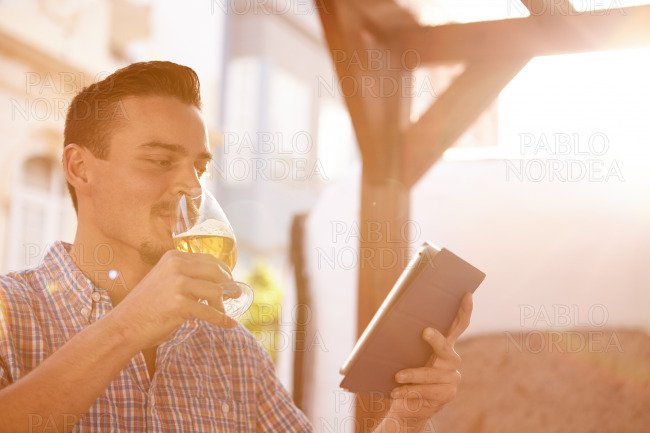 Short haired man with beer and touchpad