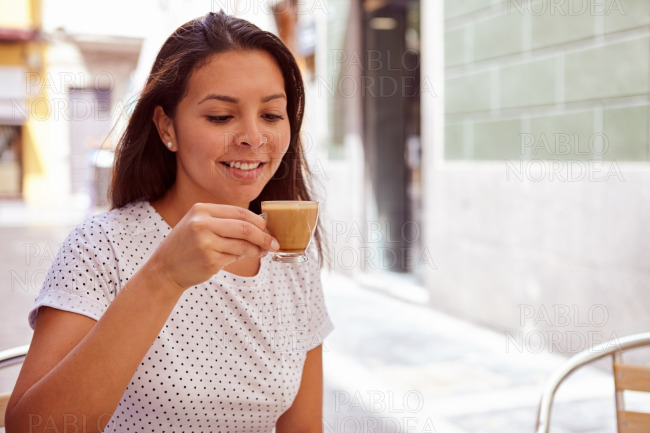 Smiling girl drinking coffee at street cafe