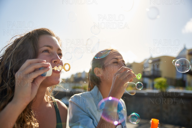 Two charming young ladies blowing bubbles