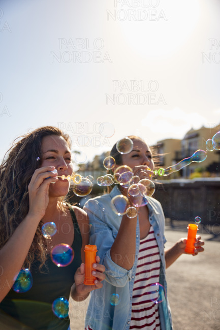 Two girls blowing strings of bubbles